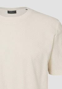 T-shirt blanc à manches courtes, col rond texturé avec un motif carré subtil et étiquette noire de la marque S.Oliver à l’intérieur du col.