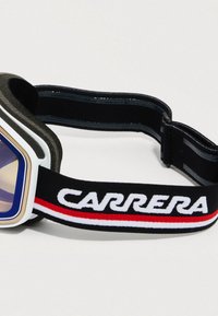 Skibriller med geometrisk design, mørk ramme, blåtonede linser, og et sort elastisk bånd med hvit "CARRERA" logo og rød accent.
