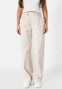 Lichtbeige wijde benen broek van een gladde stof, met voornaad, een knoopsluiting en een elastische tailleband voor comfort.