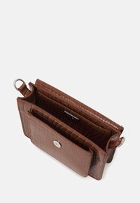 Brun pung i imiteret læder med krokodilletekstur, med tryklås, to indvendige rum og en ring til fastgørelse.