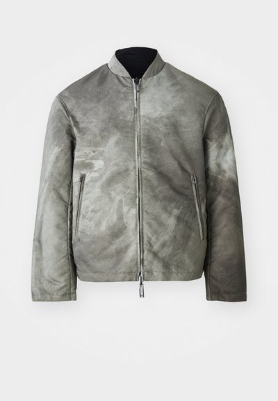 Siva bomber jakna z mat površino, z visokim ovratnikom, zadrgo in dvema stranskima žepoma. Tkanina ima teksturirano, rahlo vzorčasto površino.