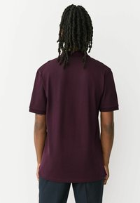 Tricou polo bordo cu mâneci scurte, din bumbac, cu croială dreaptă și design simplu al gulerului, prezentat din spate.