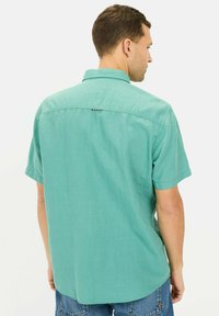 Korte mouw, knoopshirt in lichtturquoise stof met een relaxte pasvorm, rugdeeldetails en een ronde zoom.
