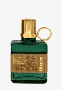 Grønn glassparfymeflaske med gullhette og ring. Trelabel viser detaljer: "Svart pepper, Sypress, Hvit timian, Vetiver Bourbon."