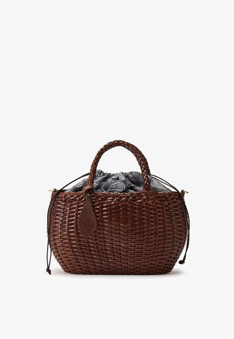 Sac à main panier tressé marron avec des poignées tressées et une doublure en tissu noir et blanc à motifs qui dépasse du dessus.