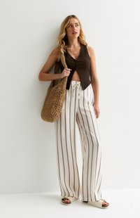 Top court côtelé marron, pantalon blanc à jambes larges avec de fines rayures brunes, sac en paille, sandales plates avec une boucle pour les orteils. Design simple et décontracté.
