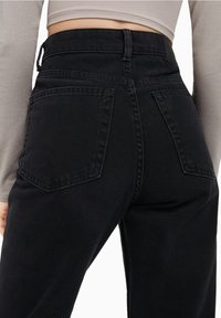 Svarta högmidjade jeans med en jämn denimtextur, utrustade med två bakfickor och en figurnära design som framhäver kroppen.