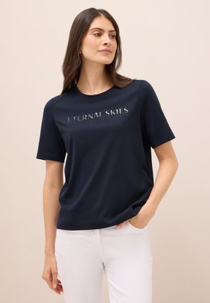 T-shirt à manches courtes bleu marine en tissu doux, arborant le texte "CIELES ÉTERNELS" en impression métallique sur le devant.