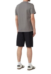 Szary t-shirt z krótkim rękawem, okrągły dekolt, w połączeniu z czarnymi szortami i białymi sneakersami, prezentujący swobodny strój z tyłu.