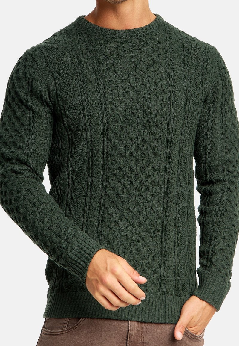 Groene gebreide trui met textuurpatronen, waaronder kabel- en diamantsteken, met geribde manchetten en zoom.