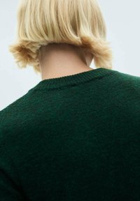 Maglione a maglia verde scuro con scollatura a girocollo e colletto a coste, mostrato dal retro. Tessuto morbido con leggere variazioni di tonalità.