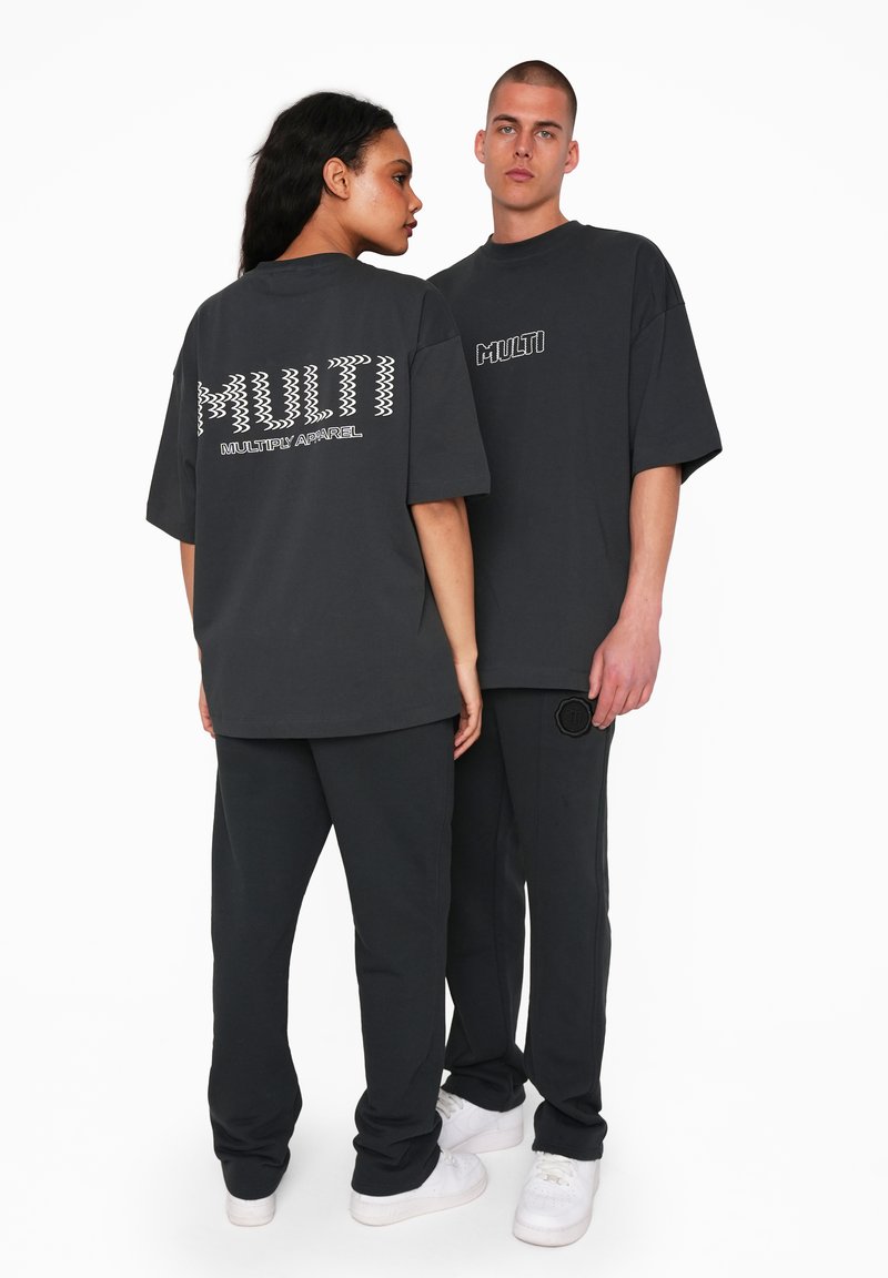 Oversized black t-shirts with white "MULTI" text and logo, paired with matching black pants and white sneakers, showcasing a casual outfit.