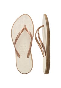 Rose gold flip-flops with textured straps, white rubber footbed, and brown sole. Features Havaianas logo on the straps and footbed.