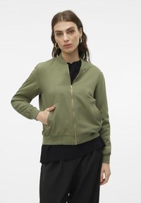 Maslinasto zelena bomber jakna s patentnim zatvaračem sprijeda, rebrastim manžetama i rubovima, koja ima bočne džepove i glatku, sjajnu teksturu.