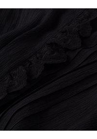 Černá tkanina s texturovaným vzhledem, s ruflovaným okrajem. Materiál má jemný lesk a vrstvené záhyby.