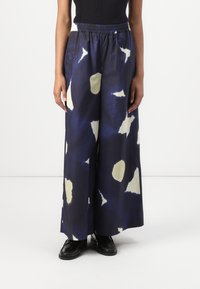 Wide-leg pants in dark blue fabric with a watercolor-style pattern in cream. Features an elastic waistband for comfort and a smooth texture.