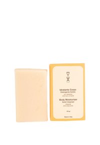 Bacchetta idratante solida di colore beige chiaro, con una consistenza liscia, accanto a una scatola arancione con testo marrone. L'imballaggio indica la presenza di profumo d'arancia e burro di karité.