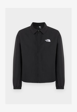 Geacă neagră cu fermoar frontal, guler, manșete elastice și logo alb The North Face pe pieptul stâng, afișată pe un fundal simplu.