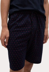 Marineblaue Shorts mit rotem Herzmuster, elastischem Bund und Kordelzug. Aus weichem Stoff, entworfen für Komfort und einfache Handhabung.