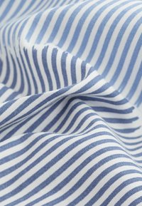 Tissu à rayures bleues et blanches avec une texture lisse, présentant des rayures étroites alternées. Matière en coton léger, délicatement drapée.