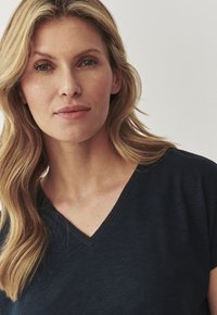 Nina, lühi varrukaga navy sinine topp, mis on valmistatud pehmest kangast. Omab peent tekstuurset viimistlust ja delikaatset tikandit kaela ääres.