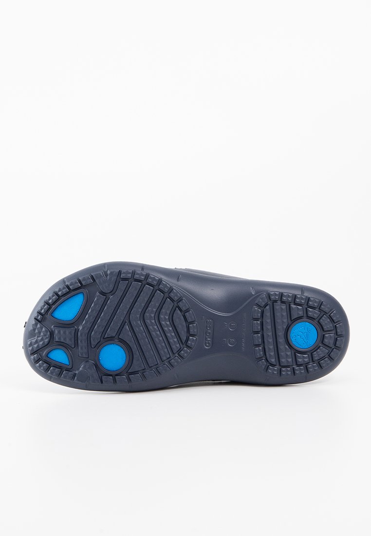 Zool van een schoen met een donkerblauwe rubberen materiaal, een textuurpatroon en heldere blauwe cirkelaccenten voor grip en stabiliteit.