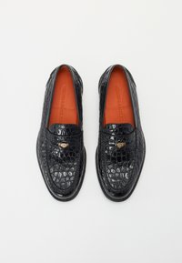 Zwarte loafers van glanzend krokodillen-embossed leer met oranje binnenzolen en een klein gouden embleem aan de voorkant. Glad, gepolijst oppervlak.