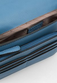 Bolso de cuero texturizado azul con un interior marrón, que cuenta con un compartimento con cremallera y detalles de acento elegantes. Etiquetado por dentro.