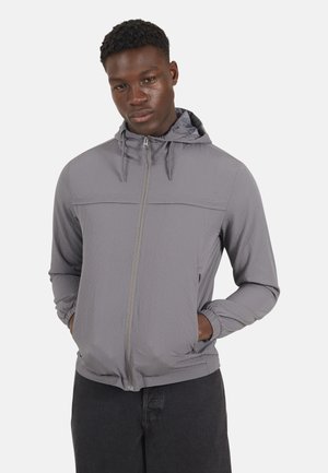 Lichte, grijze hoodie met een rits aan de voorkant, verstelbare capuchon en elastische manchetten. Textuurstof met een subtiel ruitpatroon. Voorke pockets.