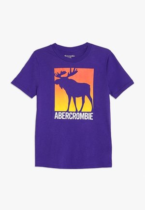 Lilla t-shirt med korte ærmer med en firkant i solnedgangsfarver med en silhuet af en elg og teksten "ABERCROMBIE" nedenunder grafikken.