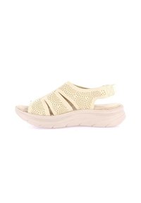 Sandalo beige aperto con design perforato, suola elevata, materiale leggero e cinturino regolabile al tallone per una vestibilità perfetta.