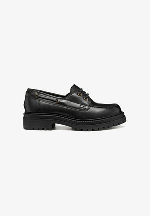 Zapato náutico negro de piel con cordones, suela de goma gruesa y ojales de metal, costuras laterales y detalle de puntera tipo mocasín.