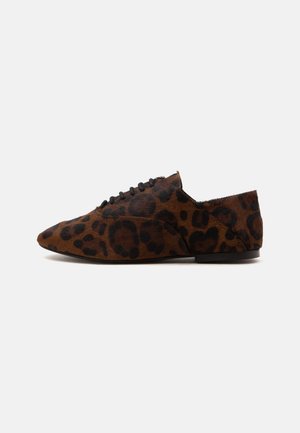 Hnedá plochá topánka s čiernymi leopardími škvrnami, so šnurovaním vpredu a nízkym podpätkom na bielom pozadí, pohľad z boku.