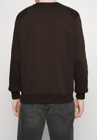 Sudadera marrón hecha de tela suave, con escote redondo, puños y dobladillo acanalados. Vista trasera, con diseño sencillo y sin logos visibles.