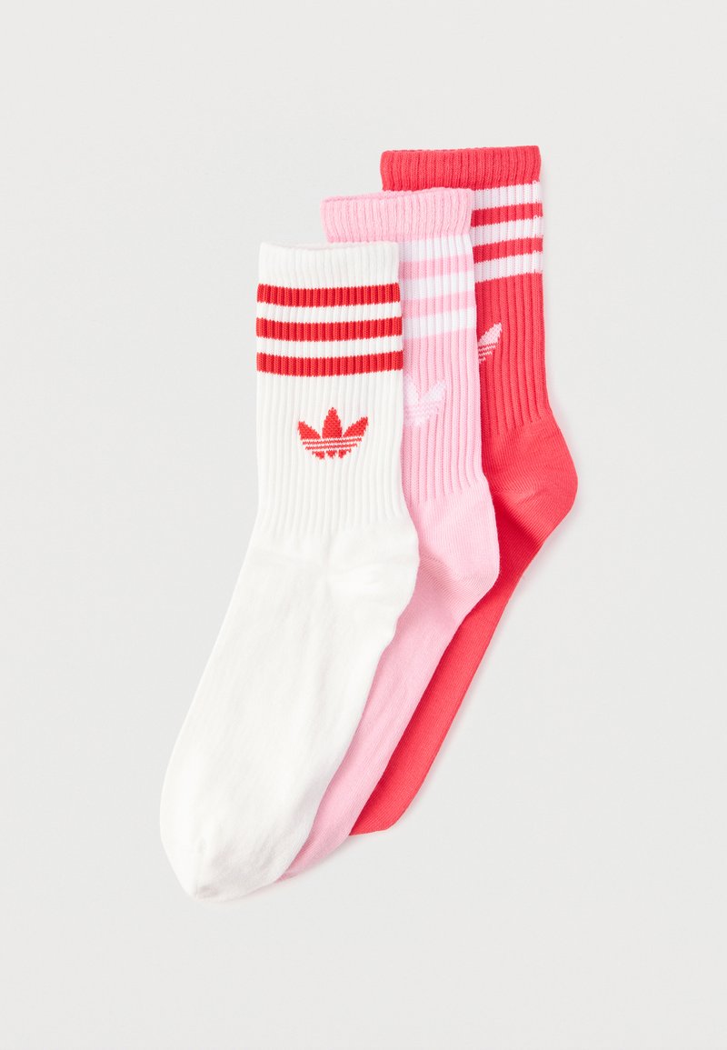 Tre paia di calzini Adidas a costine, nei colori bianco, rosa e rosso, ciascuno con due strisce e il logo trifoglio Adidas vicino alla parte superiore.
