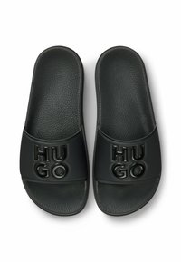 Black slide sandals with a textured footbed. The strap features raised "HU GO" lettering in the same color. Durable synthetic material.