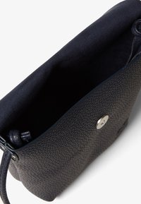 Borsa in pelle blu navy con esterno texturizzato, chiusura con bottone magnetico e interno foderato morbido. Presenta un manico flessibile da un lato.