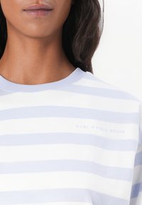 Dryžuotas švarkelis šviesiai mėlynos ir baltos medvilnės, turintis šviesinį apykaklę ir subtilų "MARC O'POLO DENIM" logotipą krūtinėje.