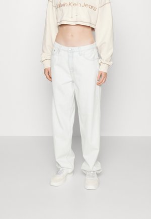 Jean en denim délavé, coupe décontractée, taille haute, cinq poches, associé à un sweat-shirt court crème et des baskets blanches.