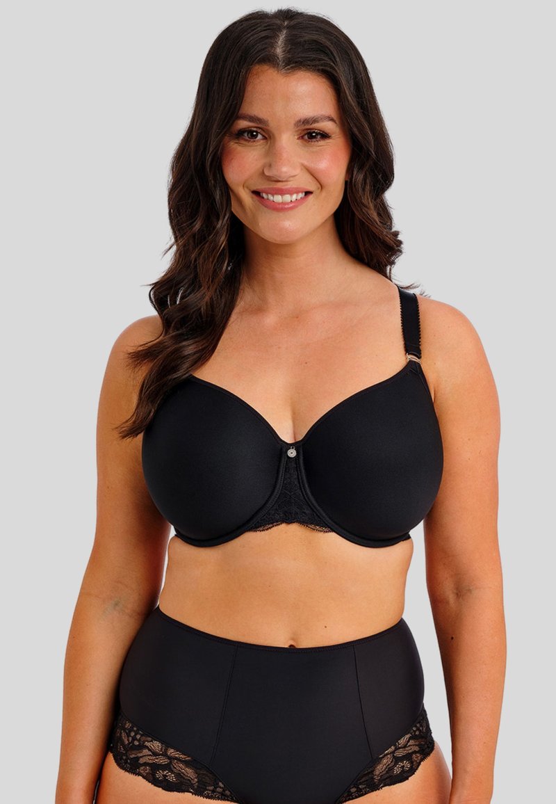 Mustan saumanmukainen rintaliivi, jossa on pitsireunus ja säädettävät olkaimet. Varustettu tukevalla metalliluilla ja pienellä koristepainikkeella keskellä.