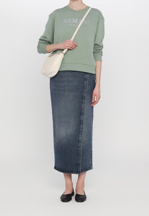 Osoba v zelené mikině, dlouhé tmavě modré džínové sukni, černých balerínách a s krémovou kabelkou přes jedno rameno.