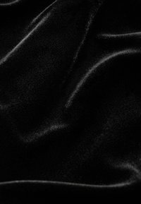 Czarna aksamitna tkanina o gładkiej fakturze, z miękkimi, błyszczącymi falami i subtelnymi refleksami światła na powierzchni.