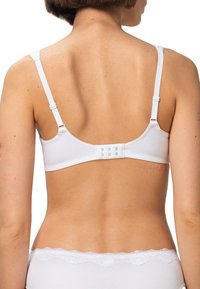 Biały bawełniany biustonosz z regulowanymi ramiączkami i zapięciem na haftki z tyłu. Gładka faktura bez widocznych wzorów.