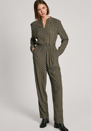 Bruine jumpsuit met een patroon, een cinched taille, lange mouwen en een kraag. De stof heeft kleine bloemenmotieven in blauw, oranje en crème.