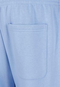 Helleblaue Baumwoll-Sweatpants mit einer einzigen aufgesetzten Tasche auf der rechten Seite, weichem, glattem Material und elastischem Bund.