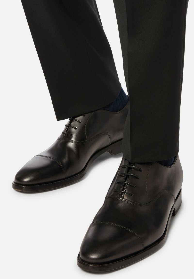 Scarpe eleganti in pelle nera con punta capitonné, dotate di una finitura liscia, chiusura con lacci e tacco leggermente rialzato.