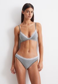 Grijze bralette en bijpassende bikini-set met kantafwerking, zachte stof en dunne bandjes, ontworpen met een driehoeksvorm en naadloze randen.