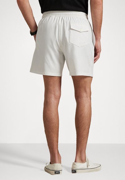 Balti elastingi juosmens šortai su užpakaline kišene. Tiesus kirpimas ir glotnaus audinio tekstūra. Derinami su šviesių spalvų sportbačiais.