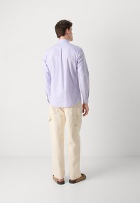 Lichtpaarse lange mouw shirt met een puntige kraag, rugplooien en knoopmanchetten, gecombineerd met crèmekleurige cargobroeken en bruine sandalen.