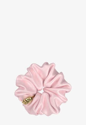Chouchou en satin rose clair avec des plis doux et un petit charm décoratif doré sur fond blanc.
